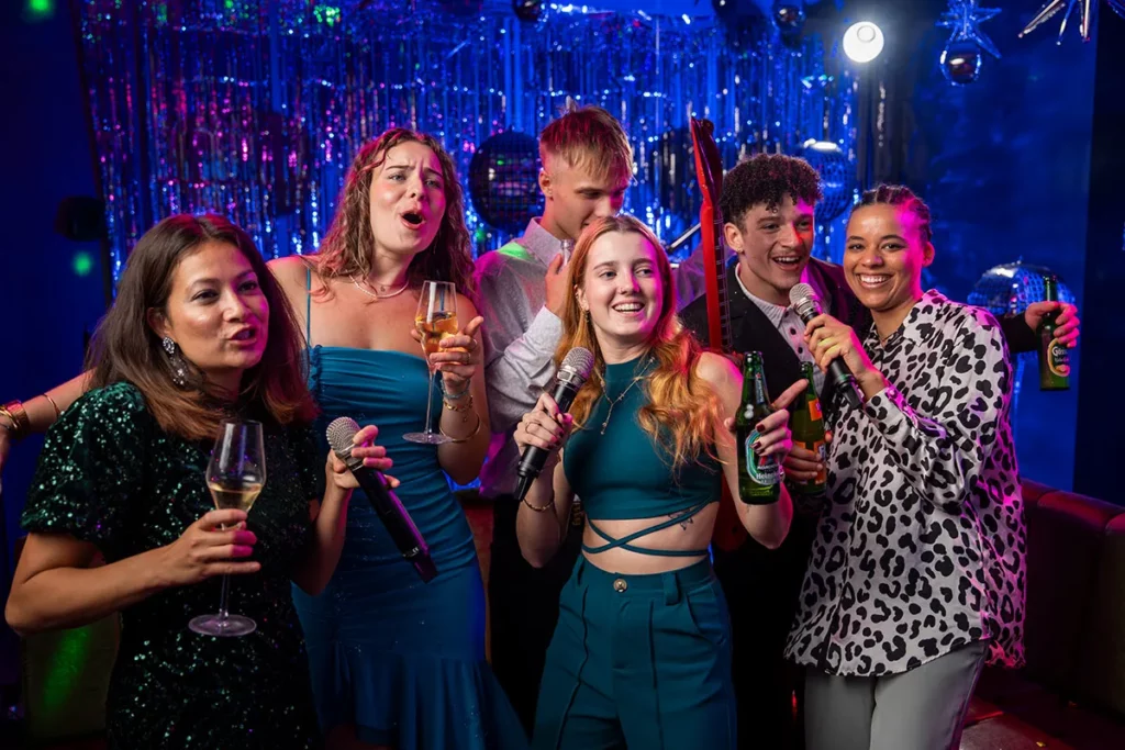 Junge Leute singen Karaoke und stoßen mit Drinks an