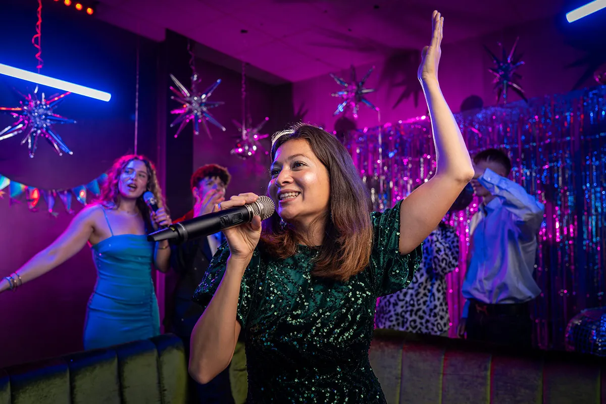 Partygruppe singt Karaoke in Bar mit Discokugel